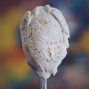 Spoonful of capns milk ice cream with a box of captain crunch in the background
